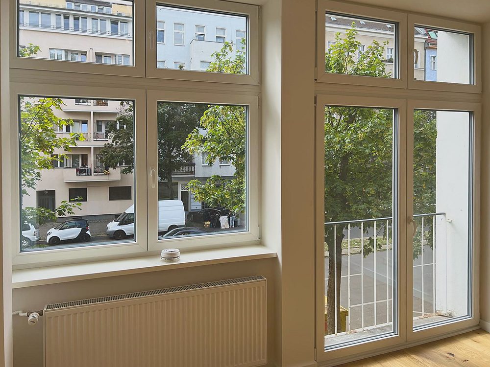 Blick aus den bodentiefen Fenstern auf die begrünte Straße
